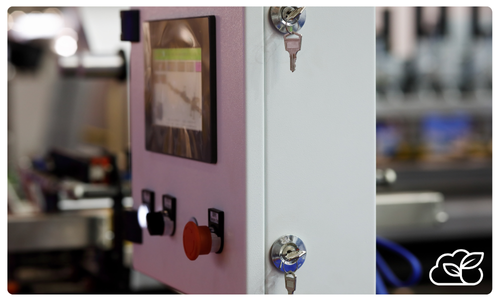 A close-up view of an industrial control panel with buttons, a screen, two keys in locks, and a leaf logo in the bottom right corner—ideal for a management system for nut and seed processors.